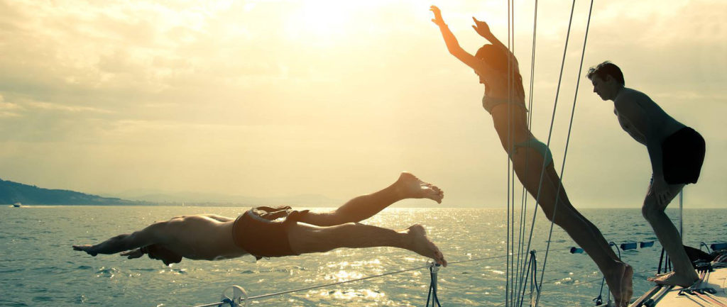 Friends Jumping Into Water From A Sailing Boat