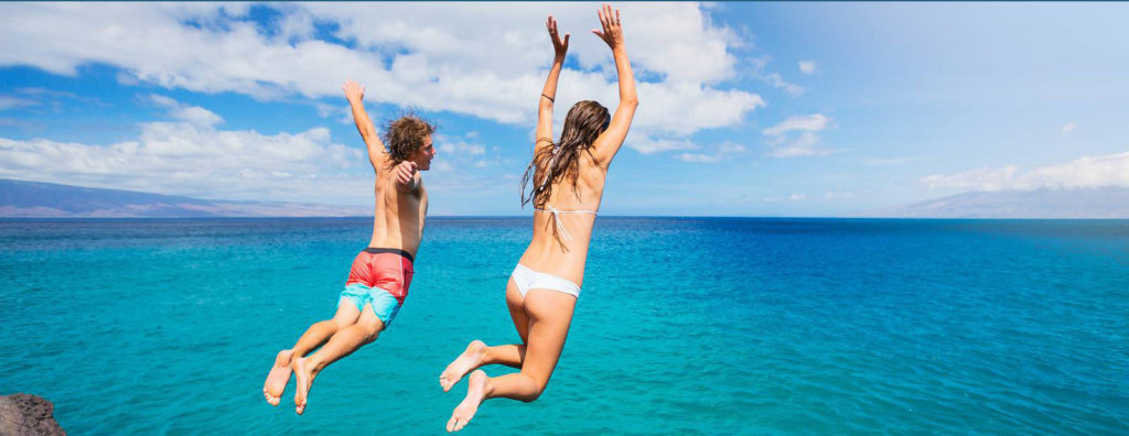 Friends cliff jumping into the ocean, summer fun lifestyle.