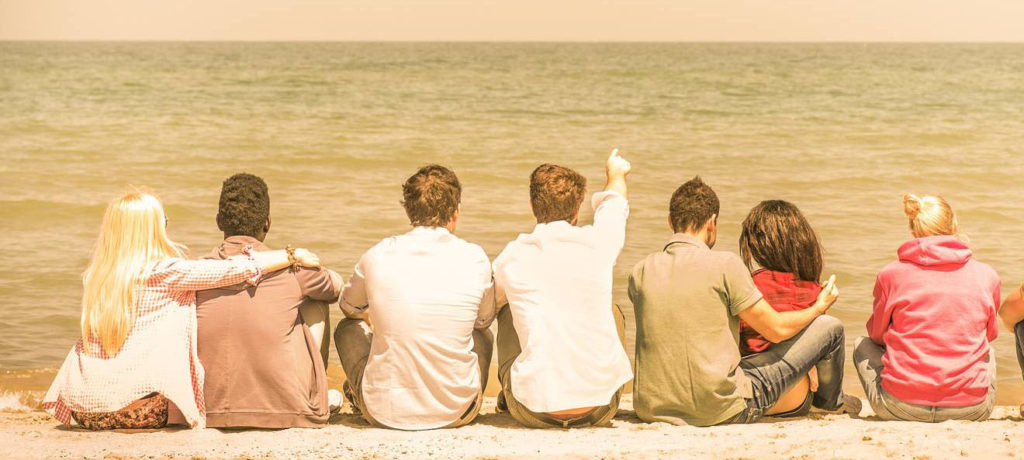 Group Of International Multiracial Friends Sitting At The Beach